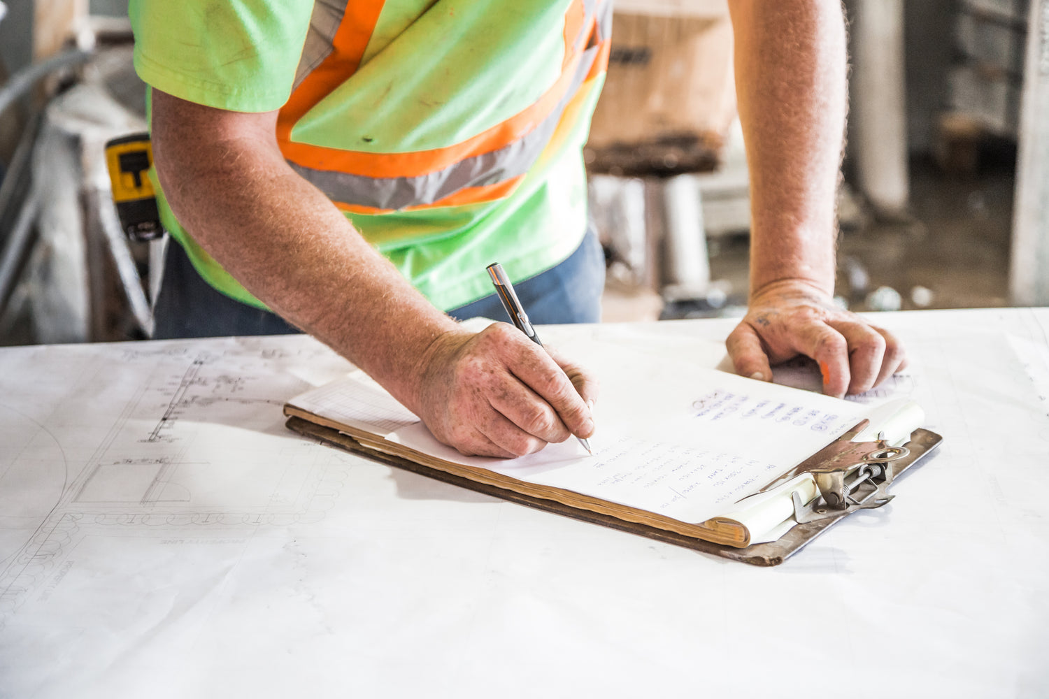 a construction worker writing on a piece of paper attached to a clipboard